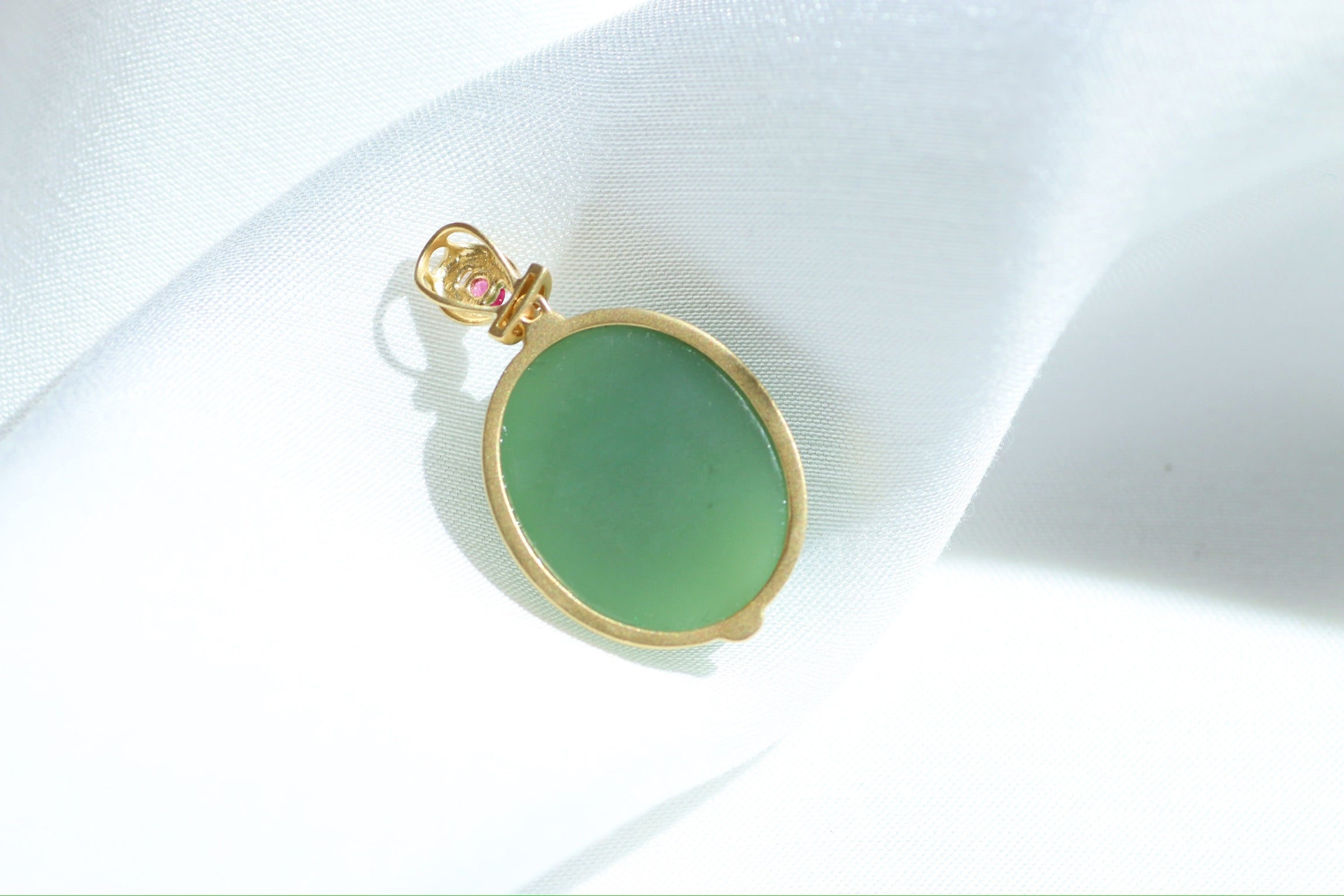 Colgante de cabujón de jade verde con engaste dorado y detalles rosas