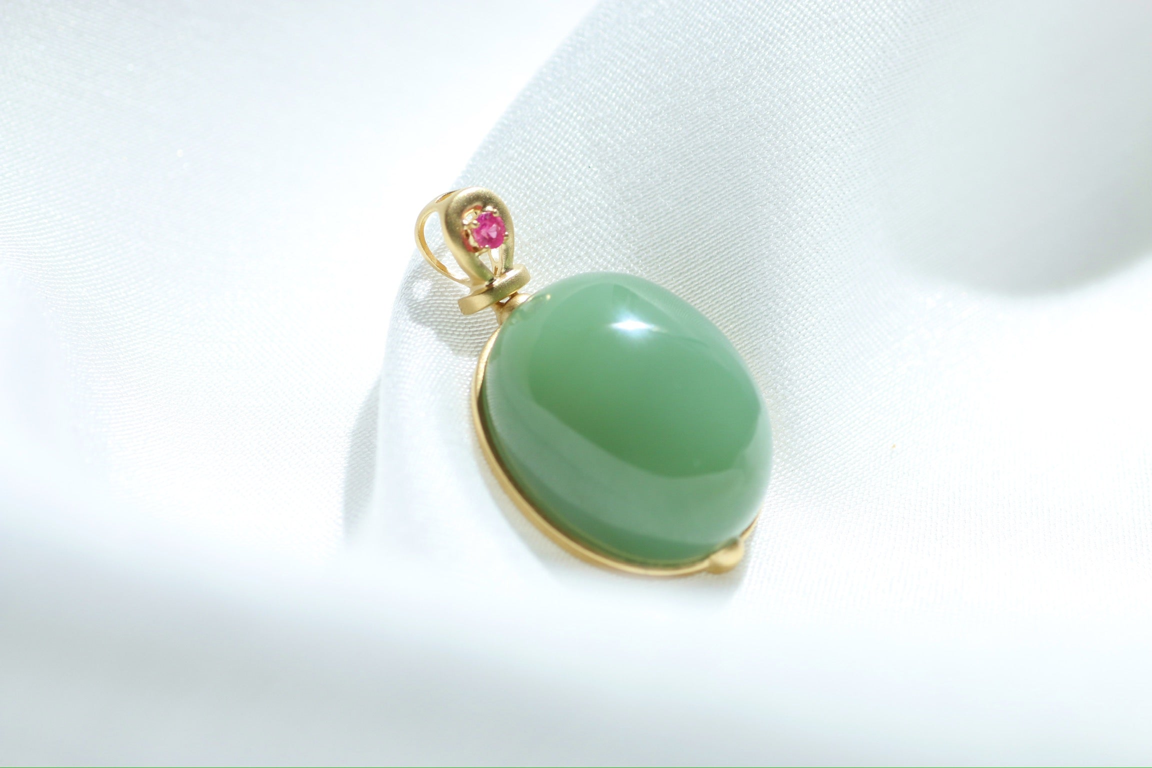 Colgante de cabujón de jade verde con engaste dorado y detalles rosas