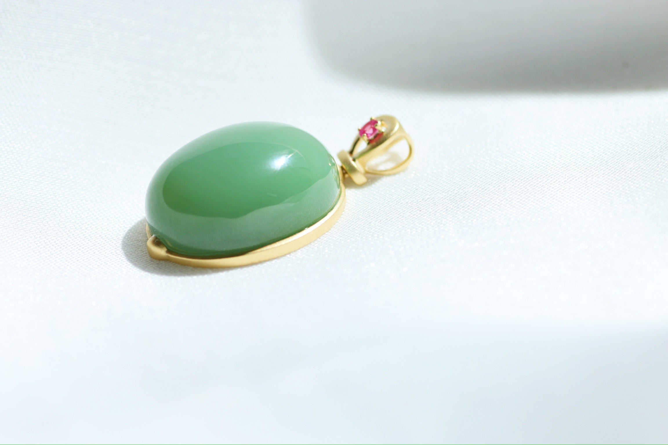 Colgante de cabujón de jade verde con engaste dorado y detalles rosas