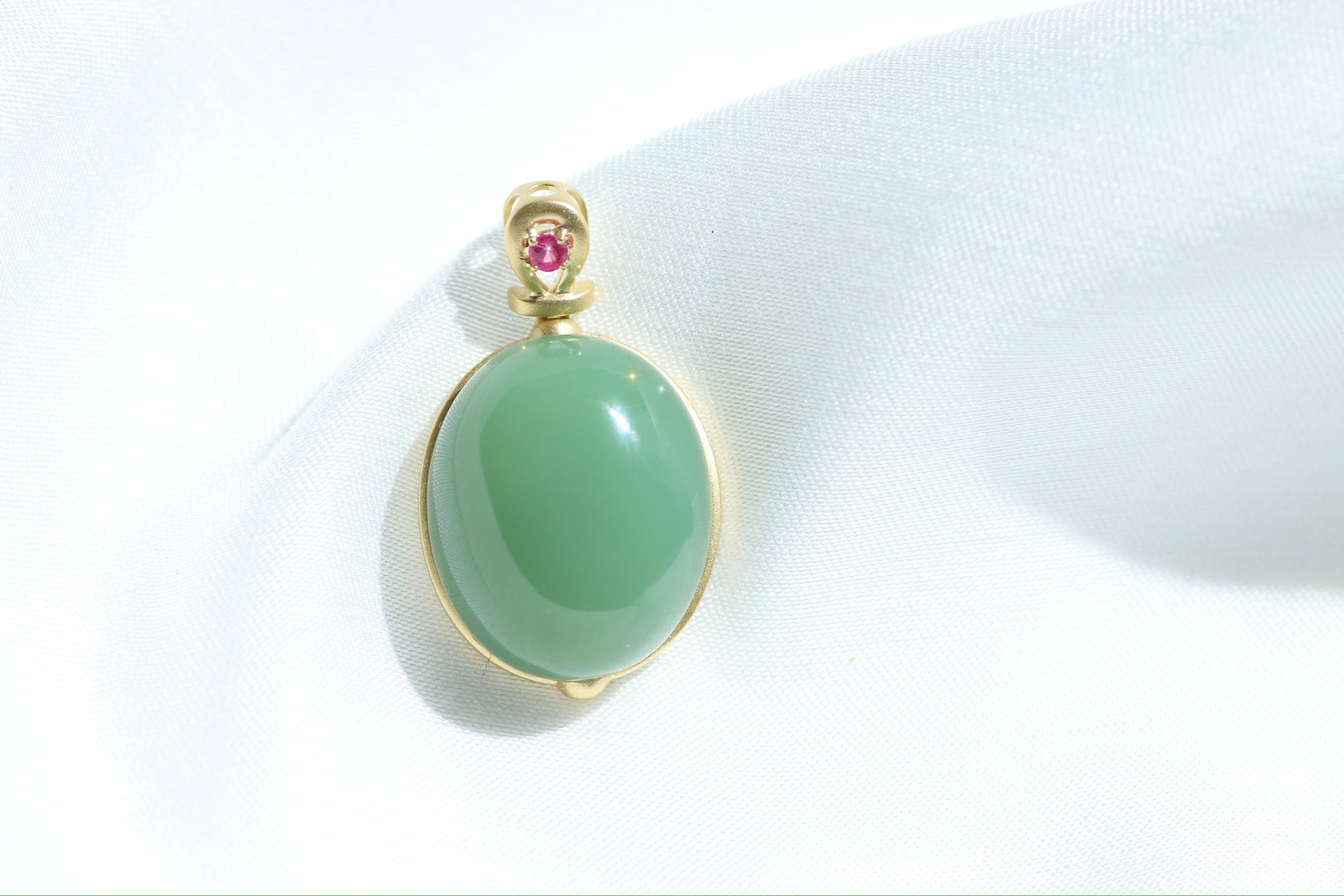 Colgante de cabujón de jade verde con engaste dorado y detalles rosas