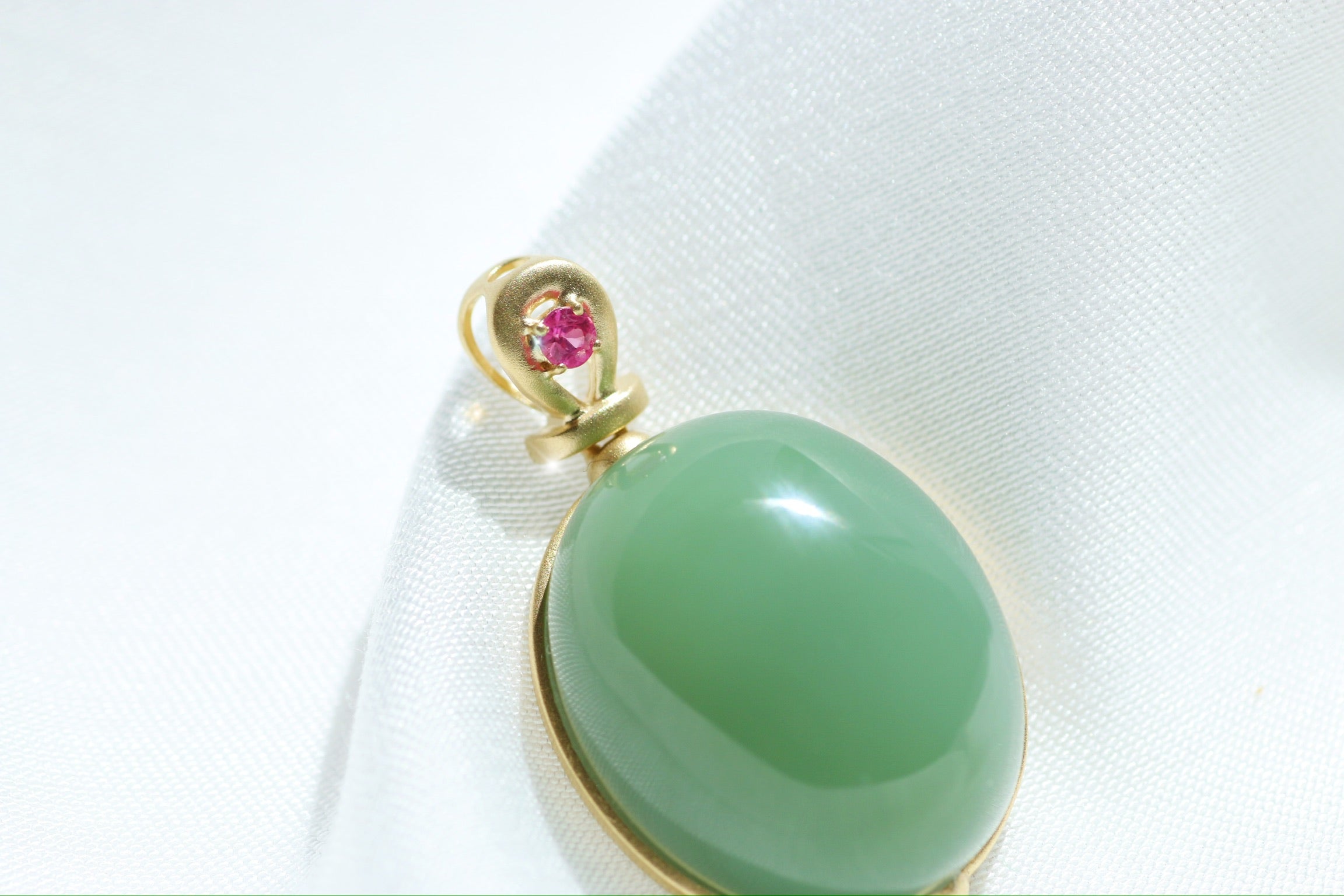 Colgante de cabujón de jade verde con engaste dorado y detalles rosas