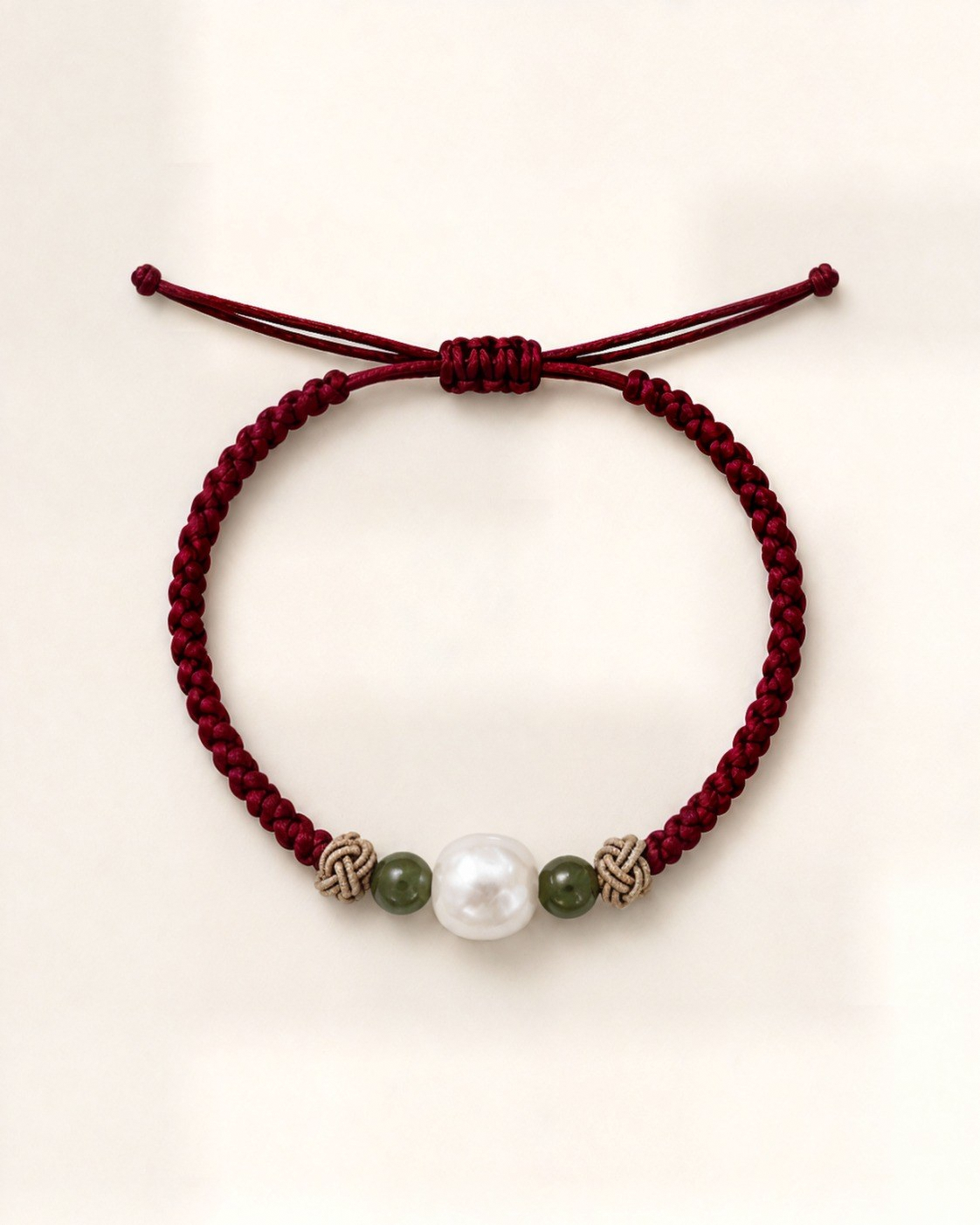 Alba in burgundy silk, with a white pearl between two green beads, pale decorative knots and a sliding closure.