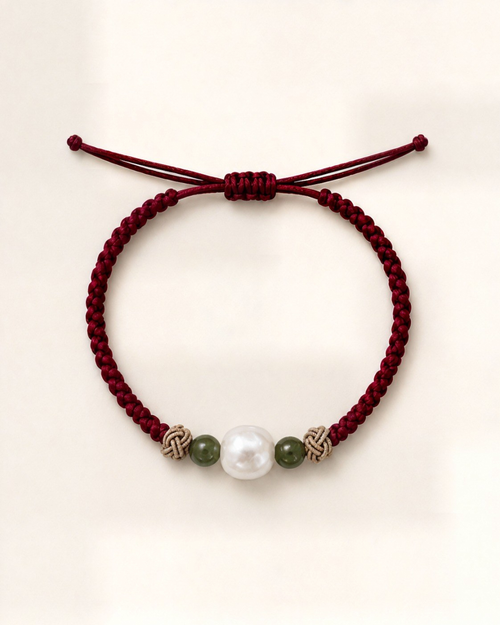 Alba in burgundy silk, with a white pearl between two green beads, pale decorative knots and a sliding closure.