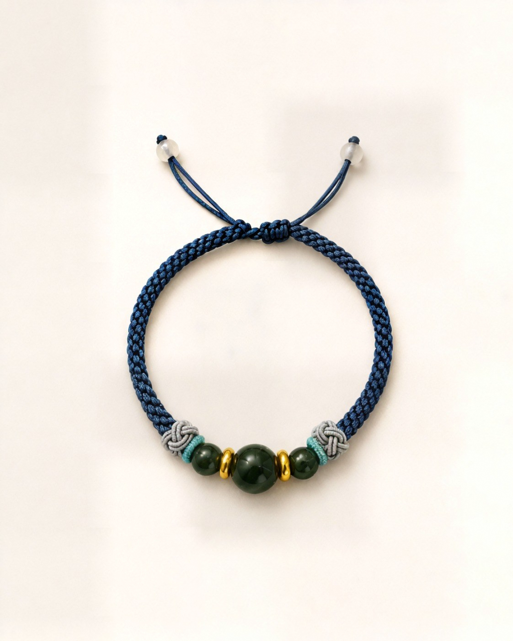 Azul Profundo pairs a steel-blue hand-braided silk cord with three green nephrite jade beads and small gold-plated bronze spacers.