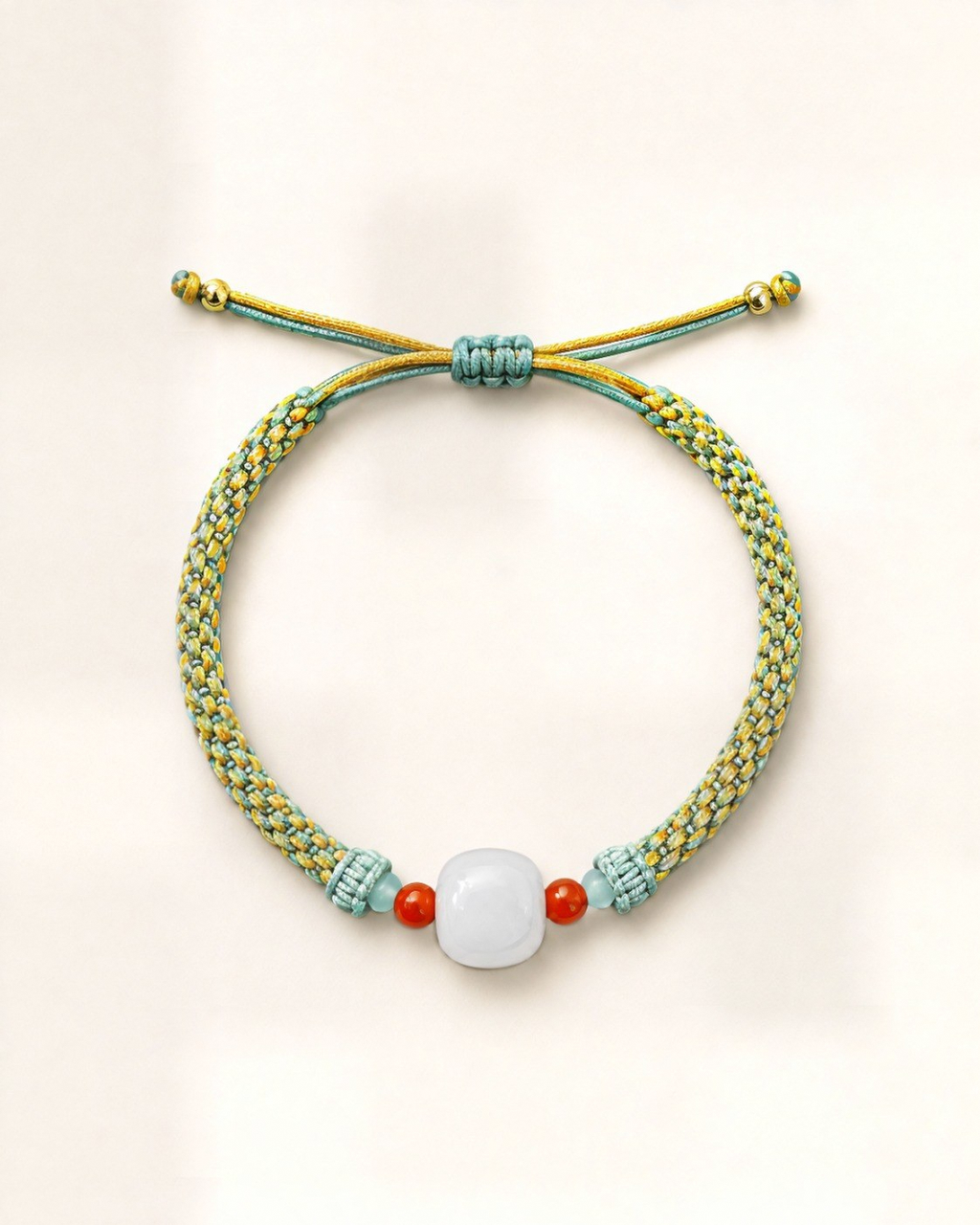 Brote combines a lime-green hand-braided silk cord with a rounded white/grey nephrite jade centre bead and two small orange agate beads.