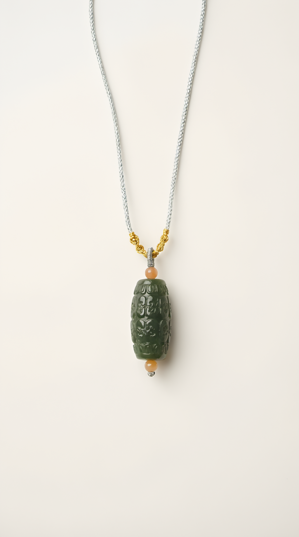 Hand-carved nephrite jade barrel pendant necklace with gold-plated bail on display