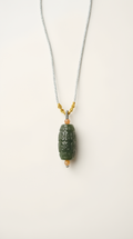 Hand-carved nephrite jade barrel pendant necklace with gold-plated bail on display