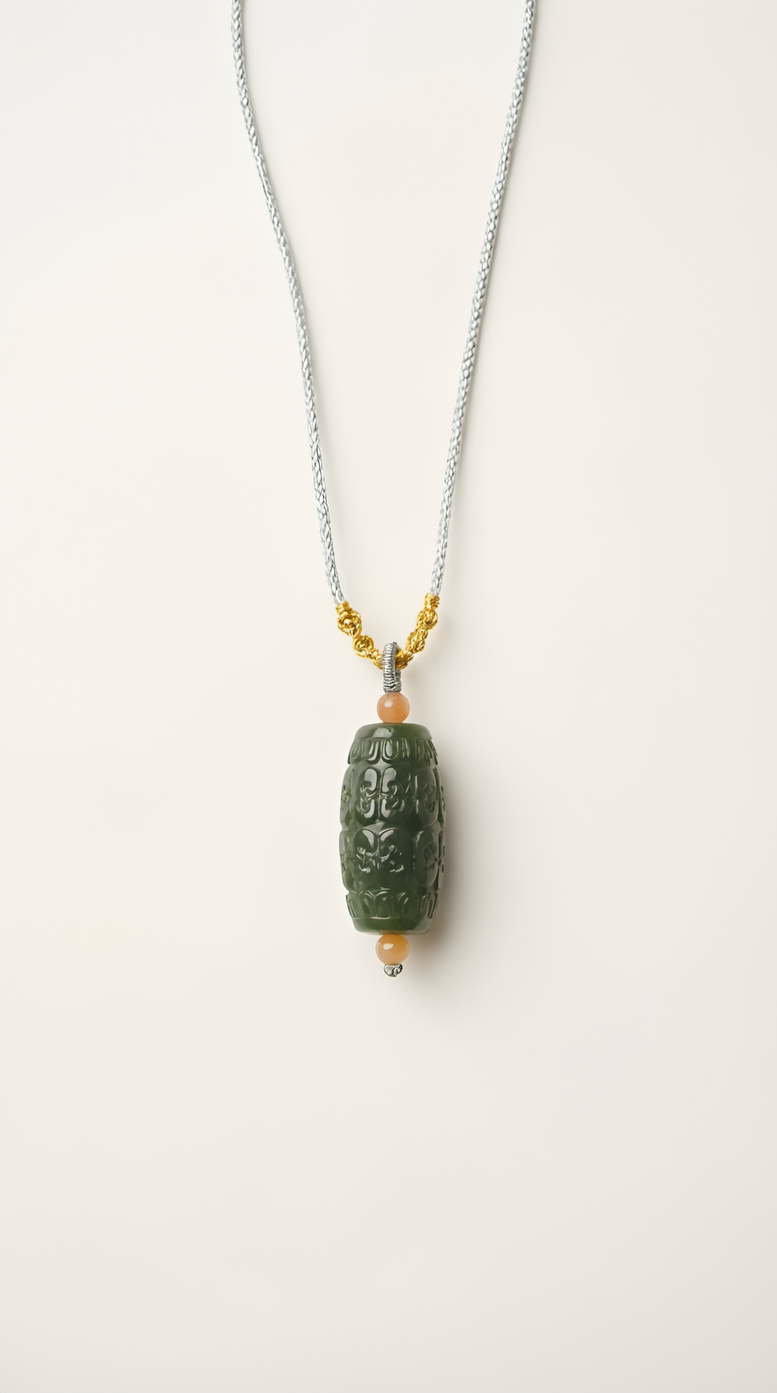 Hand-carved nephrite jade barrel pendant necklace with gold-plated bail on display