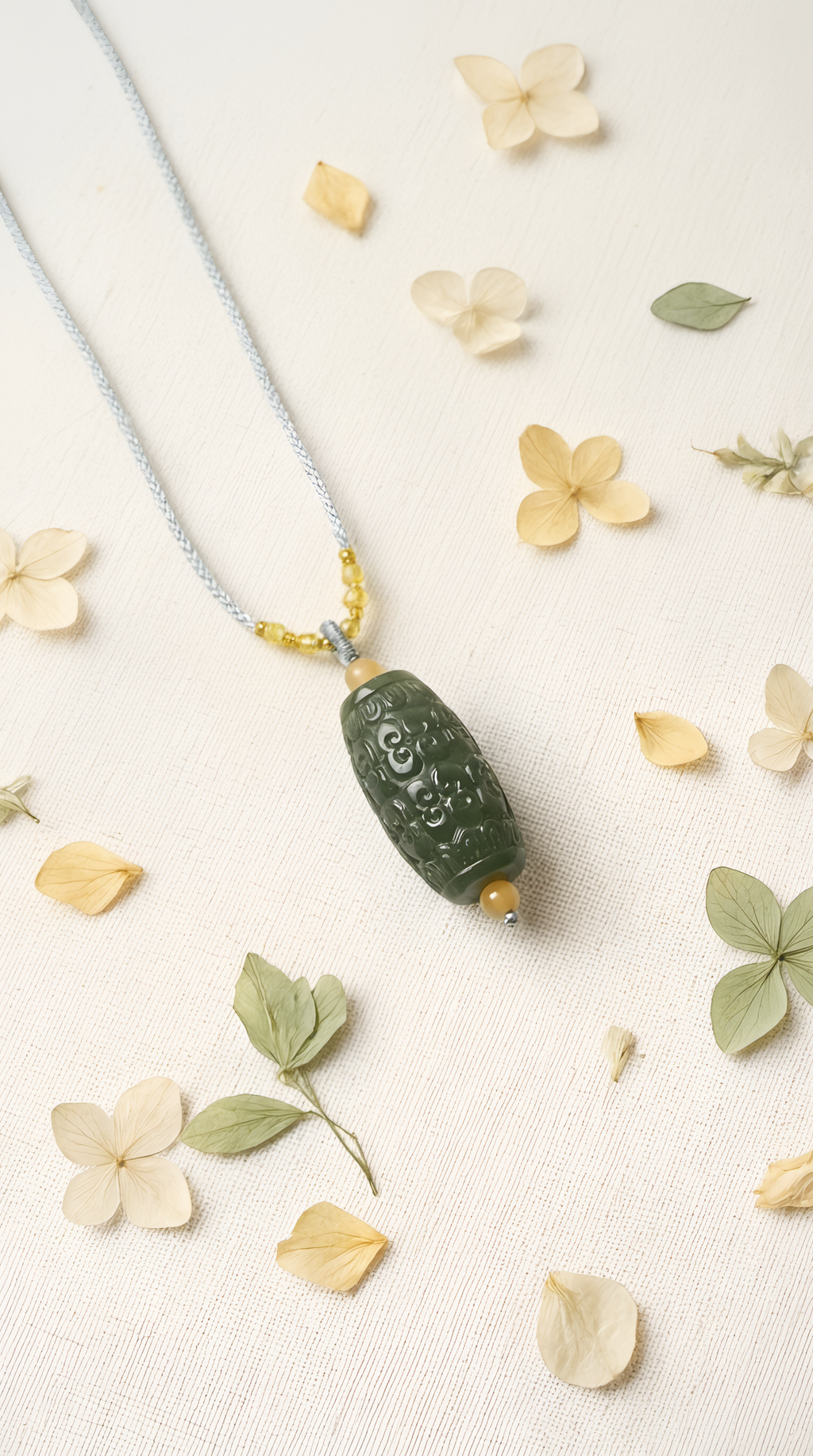 Hand-carved green jade barrel pendant showing intricate pattern detail