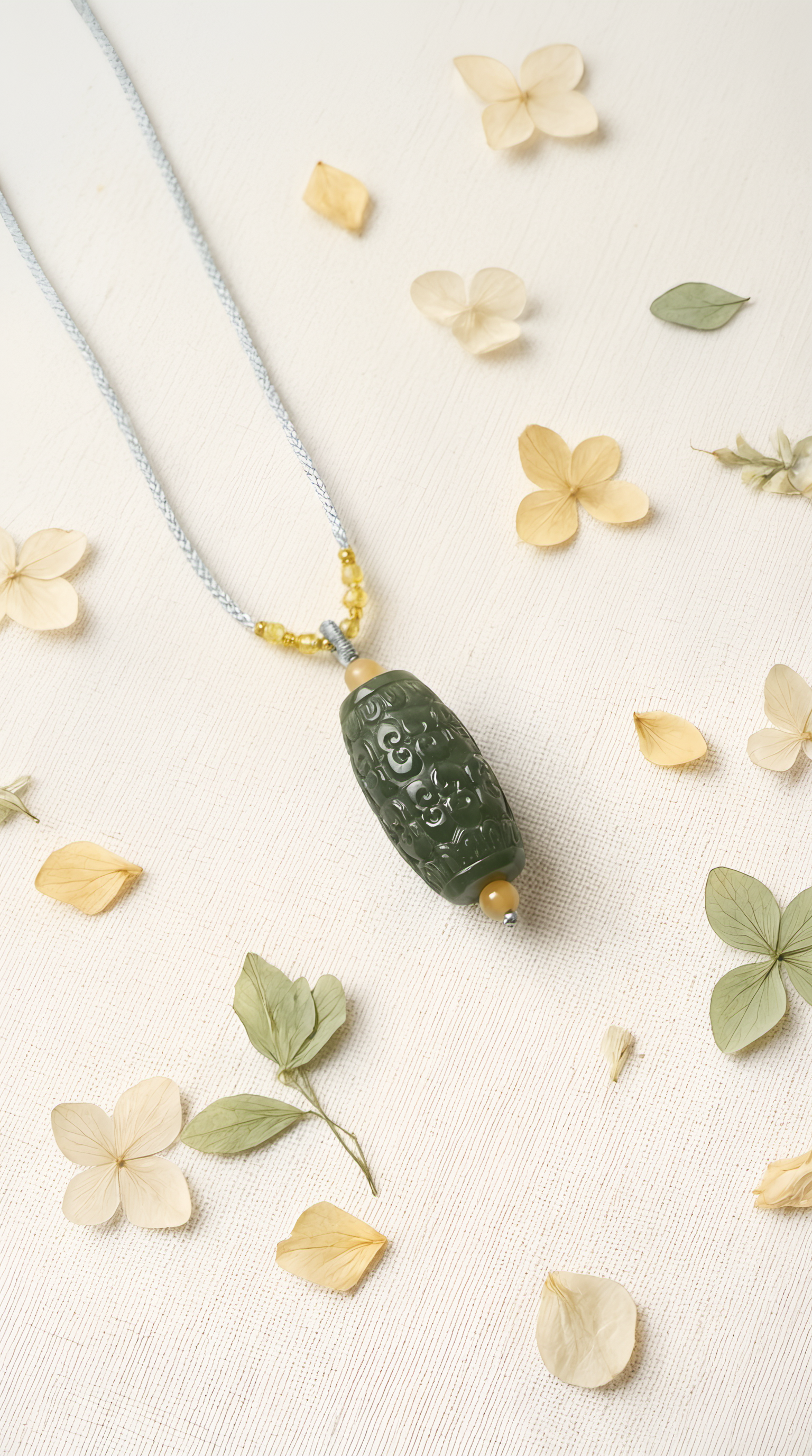 Hand-carved green jade barrel pendant showing intricate pattern detail