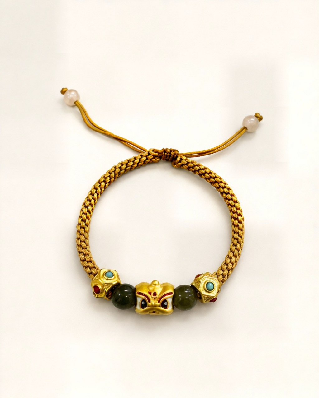 Luz de Oriente pairs a mustard hand-braided silk cord with a gold-plated bronze centre ornament featuring coloured details.