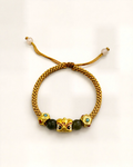 Luz de Oriente pairs a mustard hand-braided silk cord with a gold-plated bronze centre ornament featuring coloured details.