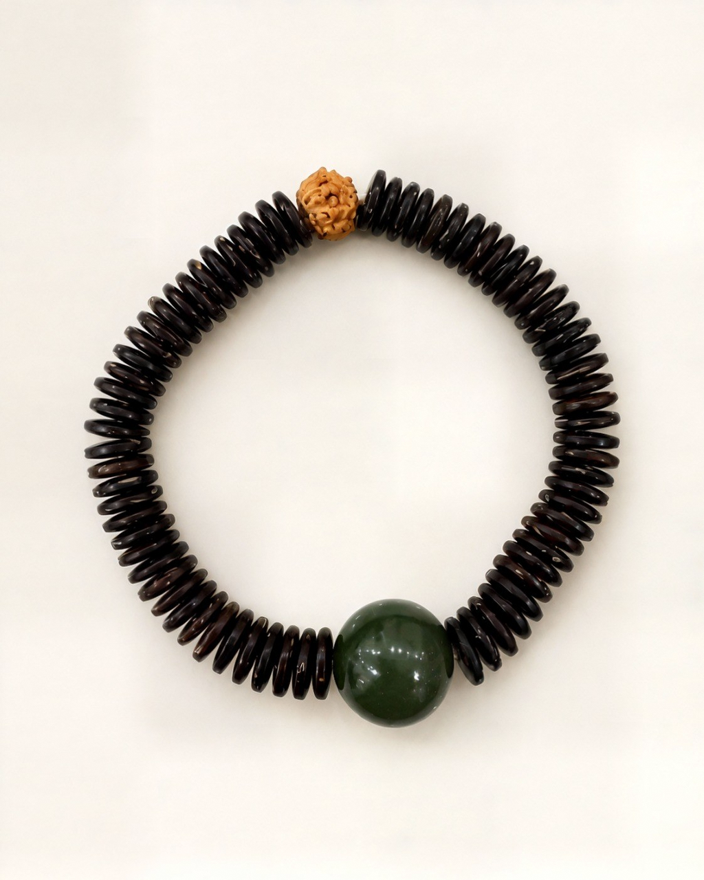 Noche Tallada combines dark bodhi discs, a natural green nephrite jade bead and a textured bodhi seed.