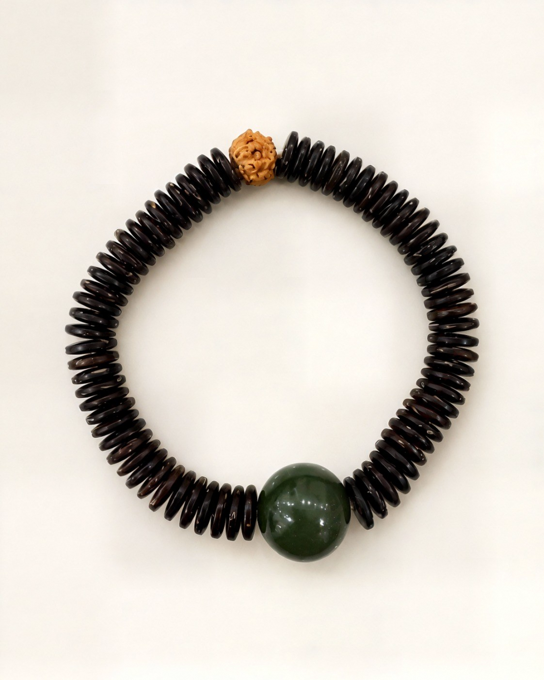 Noche Tallada combines dark bodhi discs, a natural green nephrite jade bead and a textured bodhi seed.