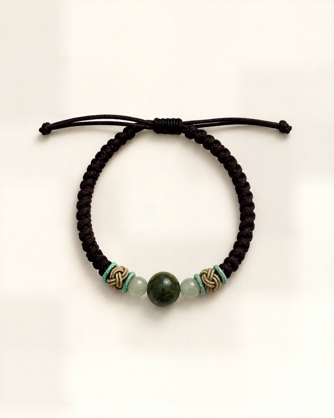 Serena combines a black hand-braided silk cord with a dark green nephrite jade centre bead and two translucent pale green side beads.
