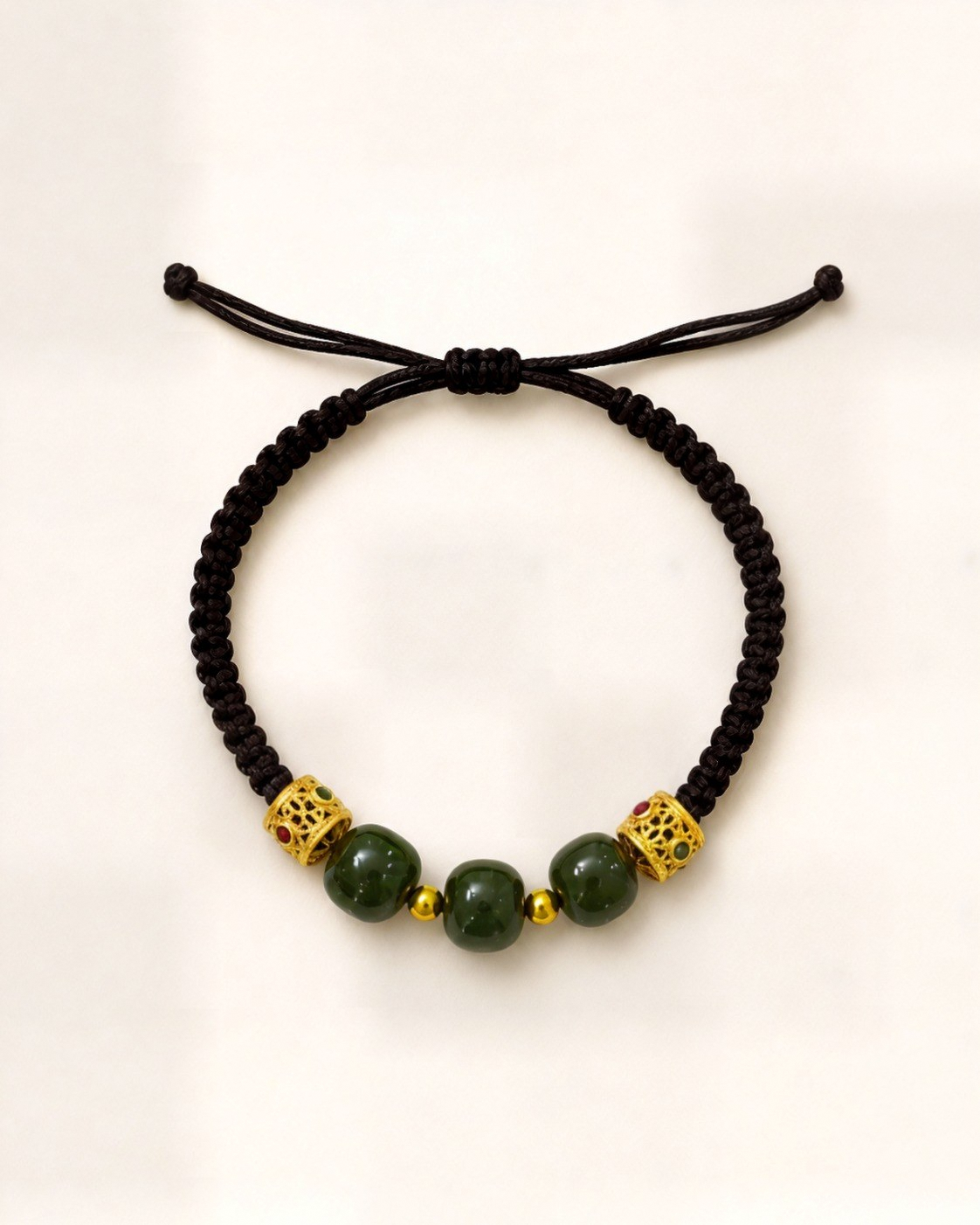Trío Real combines three green nephrite jade beads and gold-plated bronze openwork ornaments on a black hand-braided silk cord.