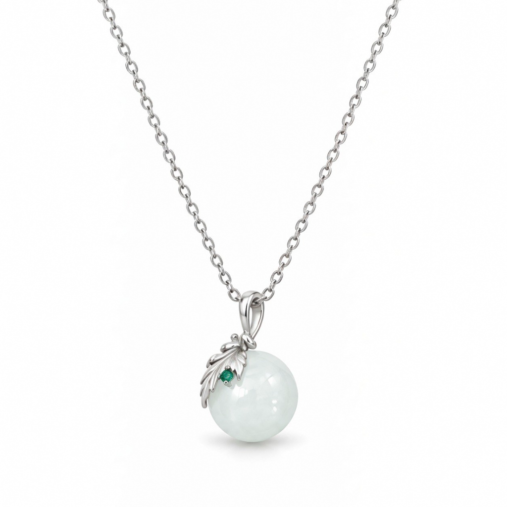 Close-up of the Flora white nephrite jade sphere with a sterling silver leaf and green cubic zirconia.