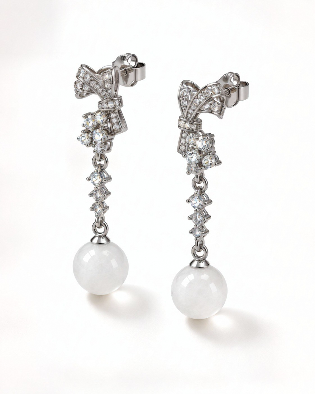 Angled view of the Gala bow earrings with cubic zirconia and white nephrite jade spheres.
