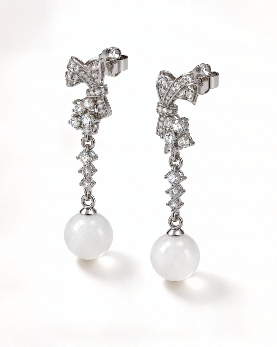 Angled view of the Gala bow earrings with cubic zirconia and white nephrite jade spheres.