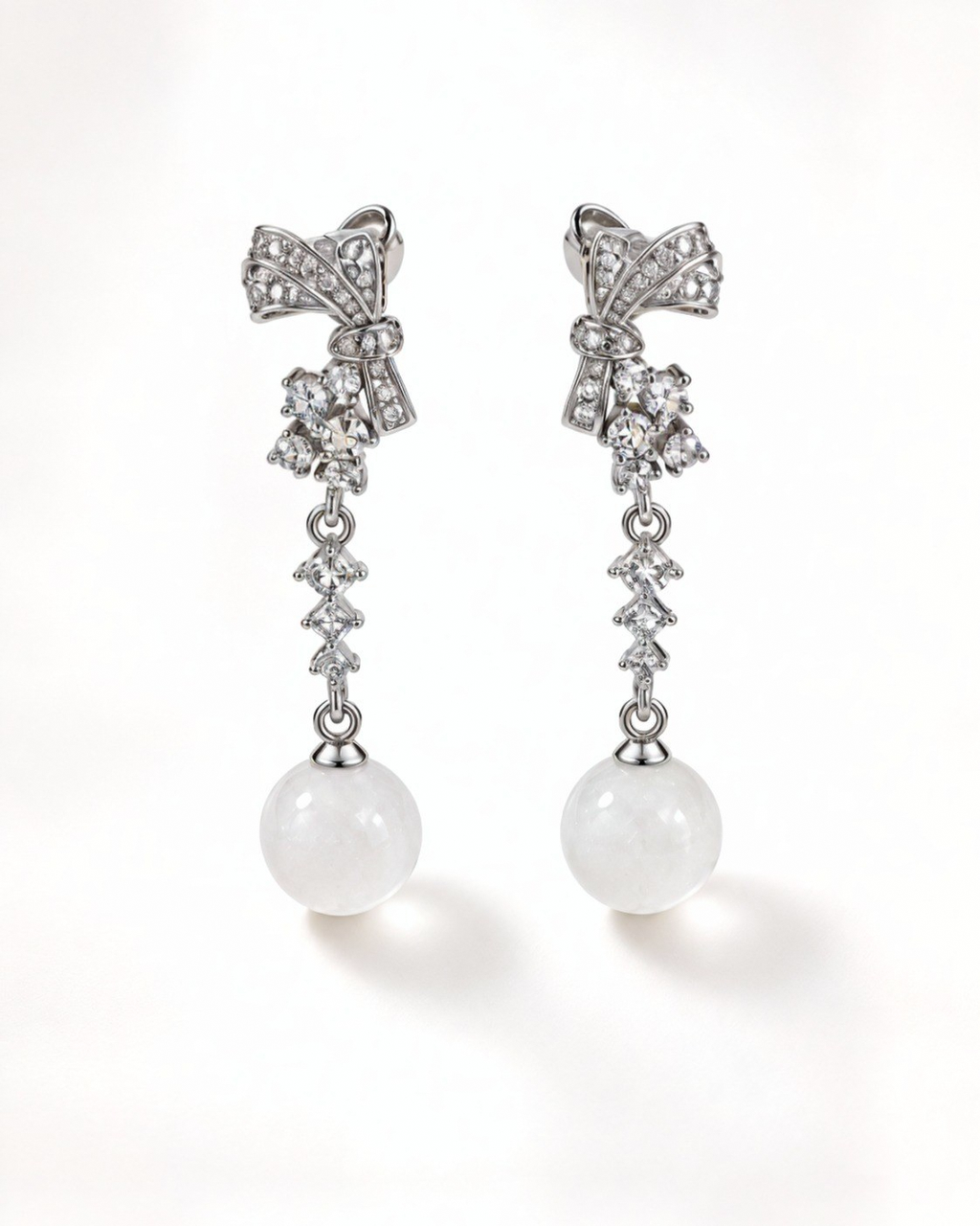 Front view of Gala sterling silver bow earrings with cubic zirconia and white nephrite jade spheres.