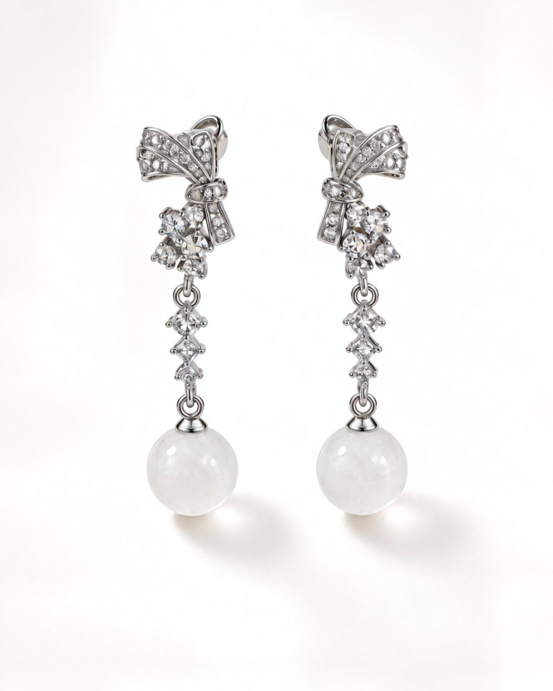 Front view of Gala sterling silver bow earrings with cubic zirconia and white nephrite jade spheres.
