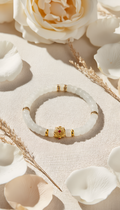 White jade bracelet with gold bead flat lay on fabric