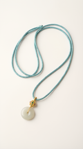 White jade disc pendant necklace with gold-plated chain on dark background